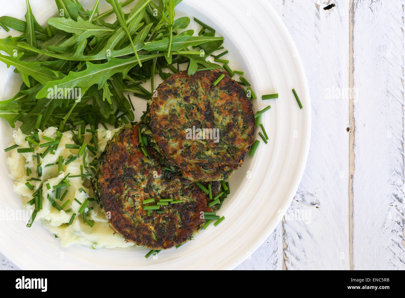 De blettes beignets de légumes avec pommes de terre en purée et de feuilles de roquette sur plaque blanche et blanc fond rugueux, copie splace Banque D'Images