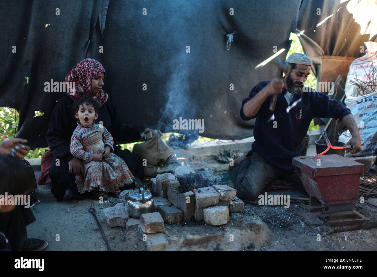 (150502) -- GAZA, 2 mai 2015 (Xinhua) -- femme palestinienne Aisha Hussein, 36 ans, et son mari Ibraheem Mustafa travailler dans la fusion des barres d'acier à l'intérieur d'une petite tente dressée sur une route principale dans la ville de Gaza, le 1 mai 2015. Aisha est une femme au foyer, elle a été l'exercice de l'une des tâches les plus difficiles pour aider son mari à surmonter leur situation de vie familiale est difficile. Au lever du soleil de tous les jours, Aisha détient un lourd marteau en acier avec ses mains rugueuses, debout devant une enclume en fer et démarrage martelant les fer à repasser après chauffage il, alors que son mari Ibrahim Mustafa, 41 ans, et dompte la compose dans Banque D'Images