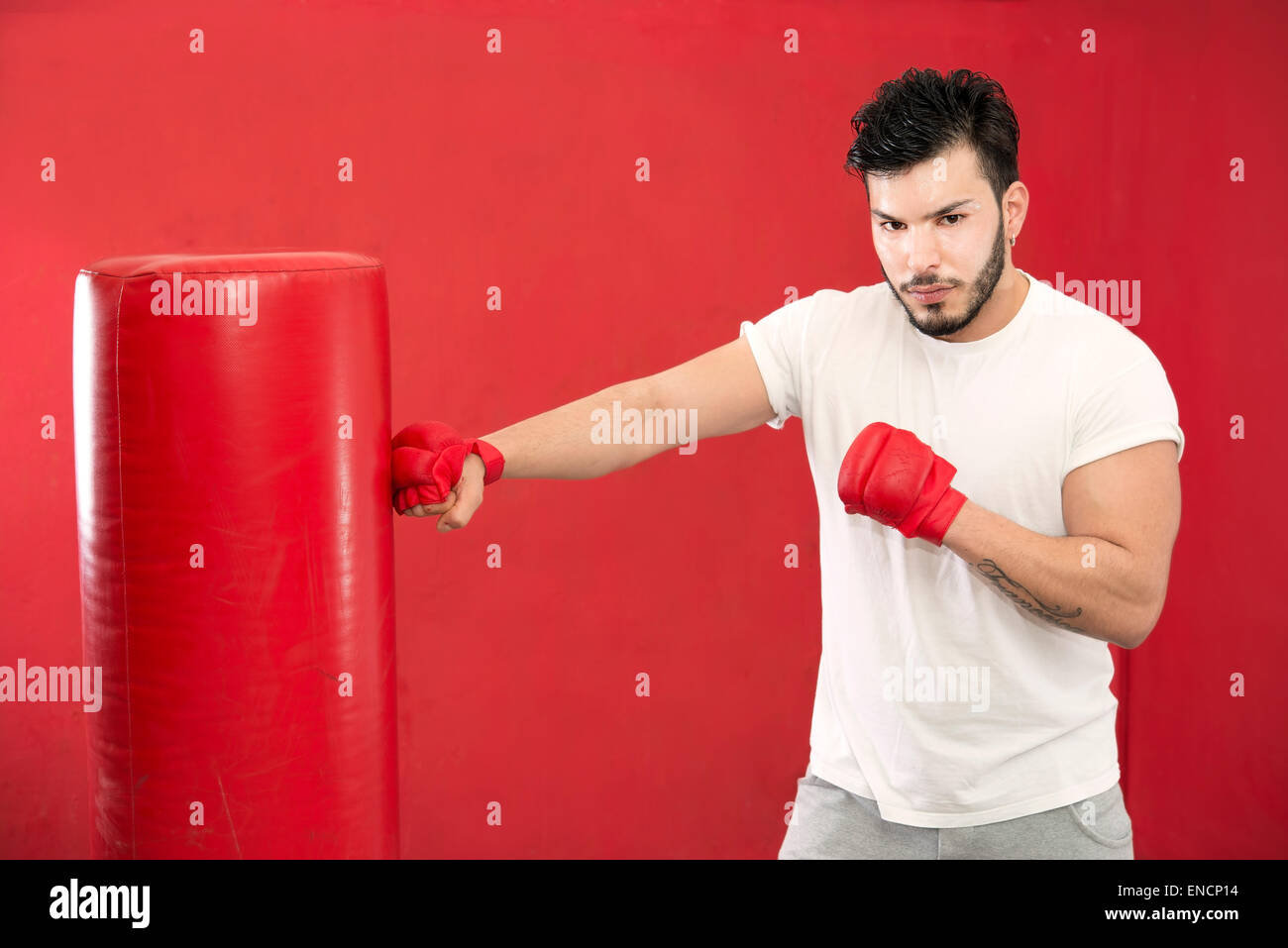 Jeune boxer dans un sac de boxe sur la formation dans un gymnase Banque D'Images