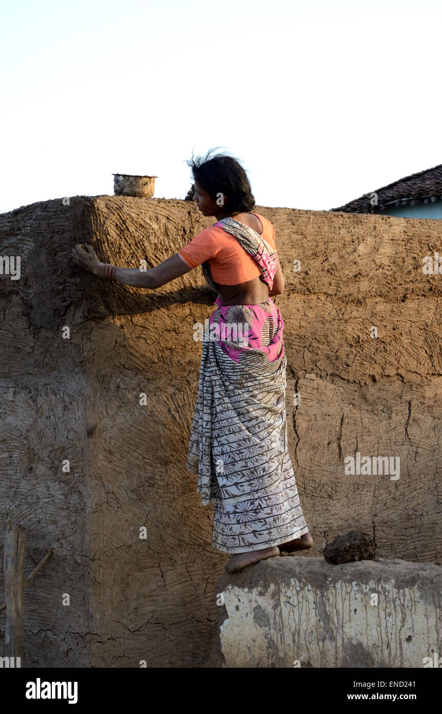 Le plâtrage des murs de la femme indienne de sa maison avec la boue et les bouses Kahna National Park Le Madhya Pradesh Inde Banque D'Images