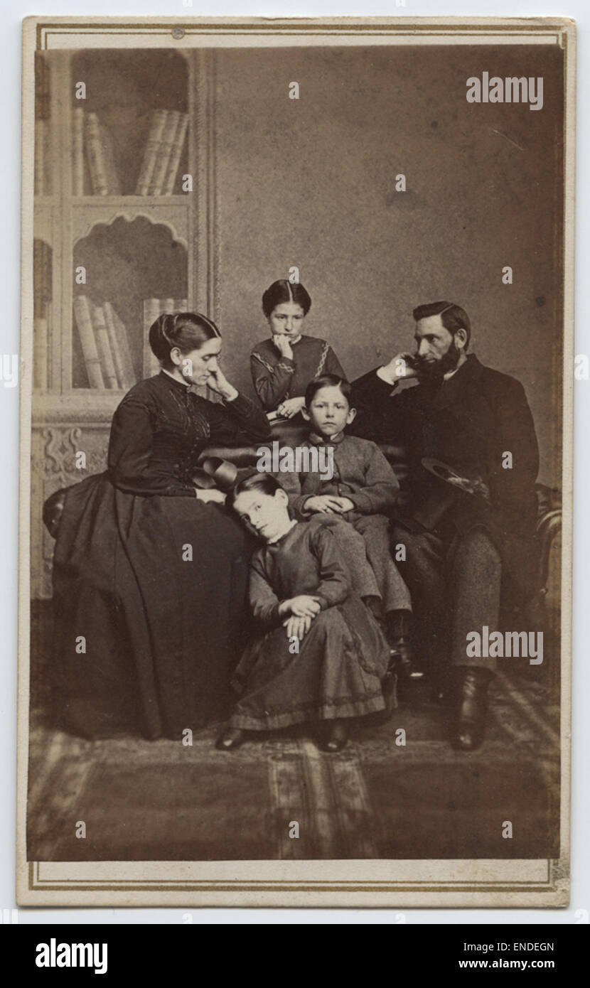 Ce portrait de famille vintage montre une femme tenant un stéréoscope, capturant un moment d'interaction familiale. Le stéréoscope était un dispositif populaire pour visualiser des images en trois dimensions, offrant un aperçu de la vie de famille dans le passé à travers la photographie Banque D'Images