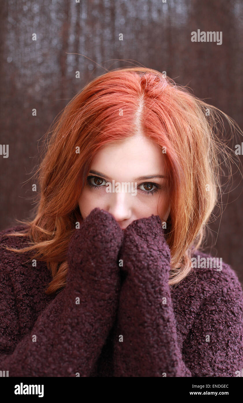 Portrait d'une jolie adolescente avec haircovering rouge son visage avec ses mains Banque D'Images