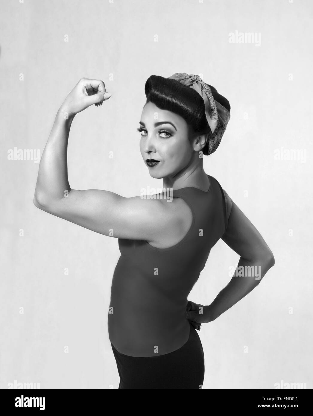 Femme brune dans une chemise bleue avec un foulard sur la tête et les cheveux dans un style rétro show-off de biceps Banque D'Images