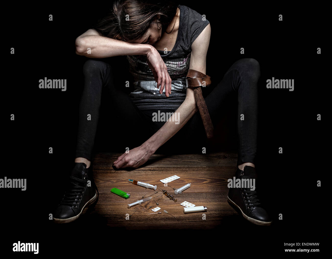 Jeune femme pose comme toxicomane, concept photo contre mur noir. Fort contraste et texture pour renforcer le message. Banque D'Images