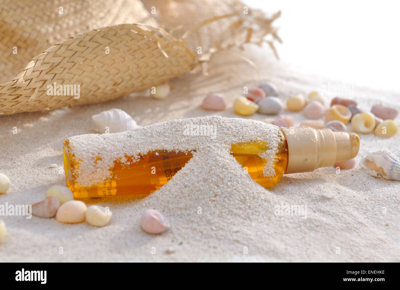 Bouteille d'huile solaire couverts par le sable avec des coquillages et cap Banque D'Images