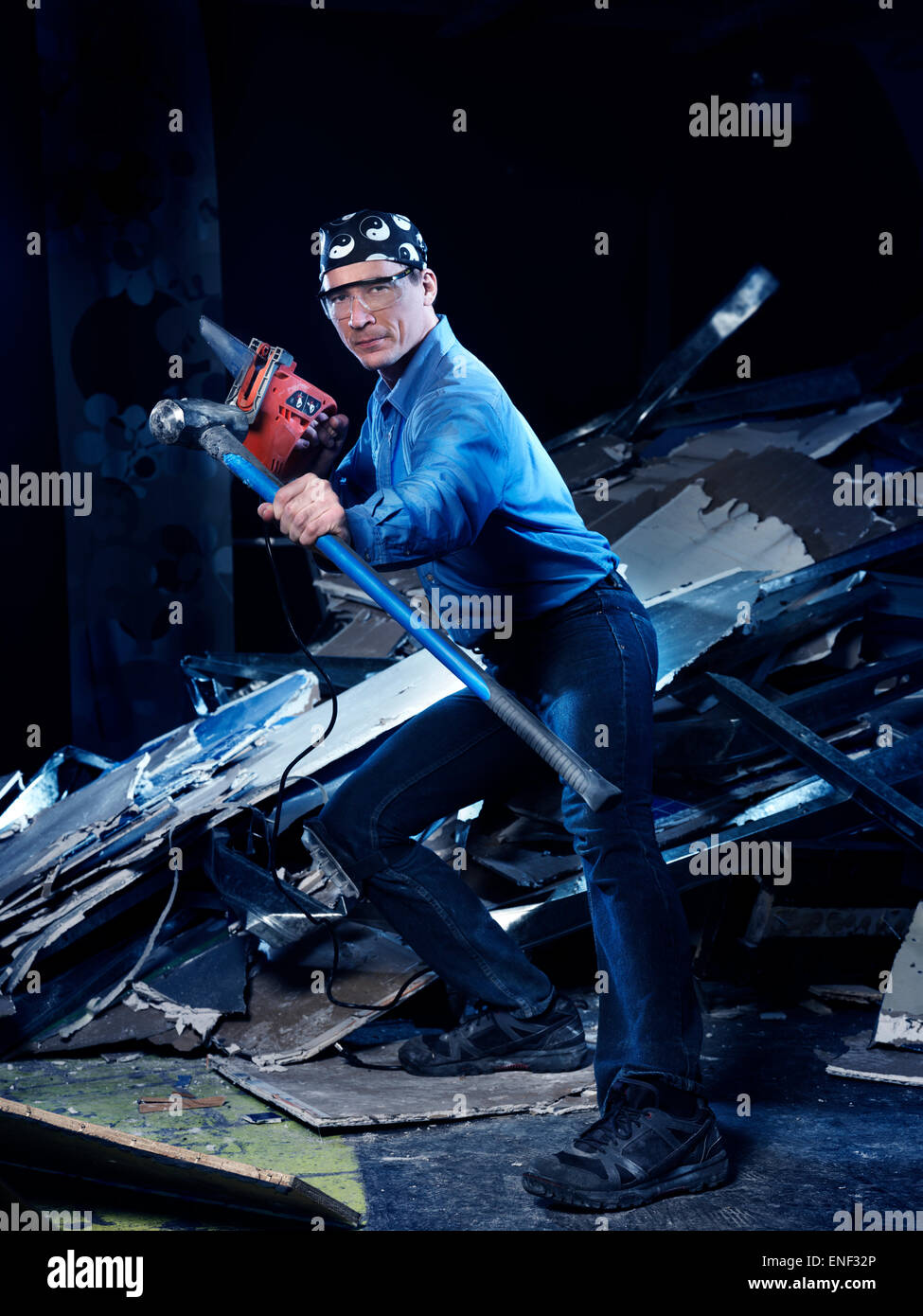 Portrait humoristique d'un homme avec un marteau et une scie dans une position de Kung Fu effectuant des rénovations et de démolition Banque D'Images