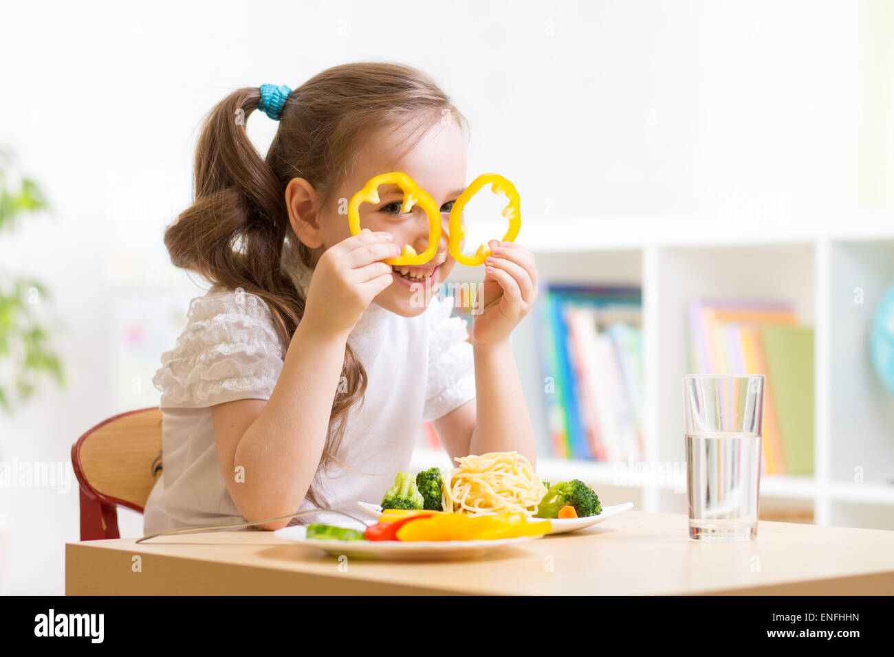 Enfant mange des aliments sains s'amusant à la maternelle Banque D'Images