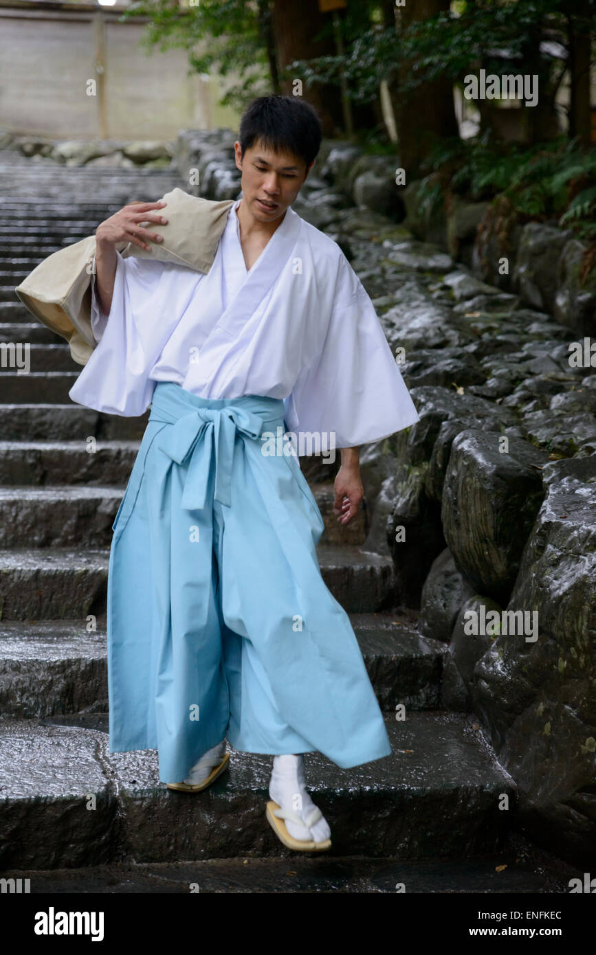 Prêtre Shinto japonais en costume traditionnel portant un sac lourd comme suit au grand culte, ISE (ISE Jingu), au Japon. Sanctuaire intérieur ; robe robes ; Banque D'Images