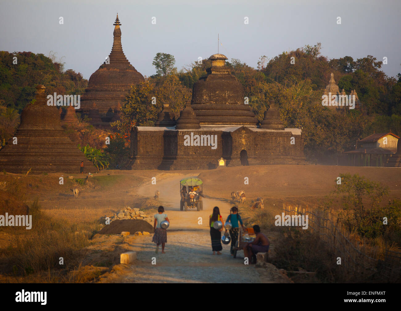 Les femmes portant de l'eau en face d'un temple bouddhiste, Mrauk U, Myanmar Banque D'Images