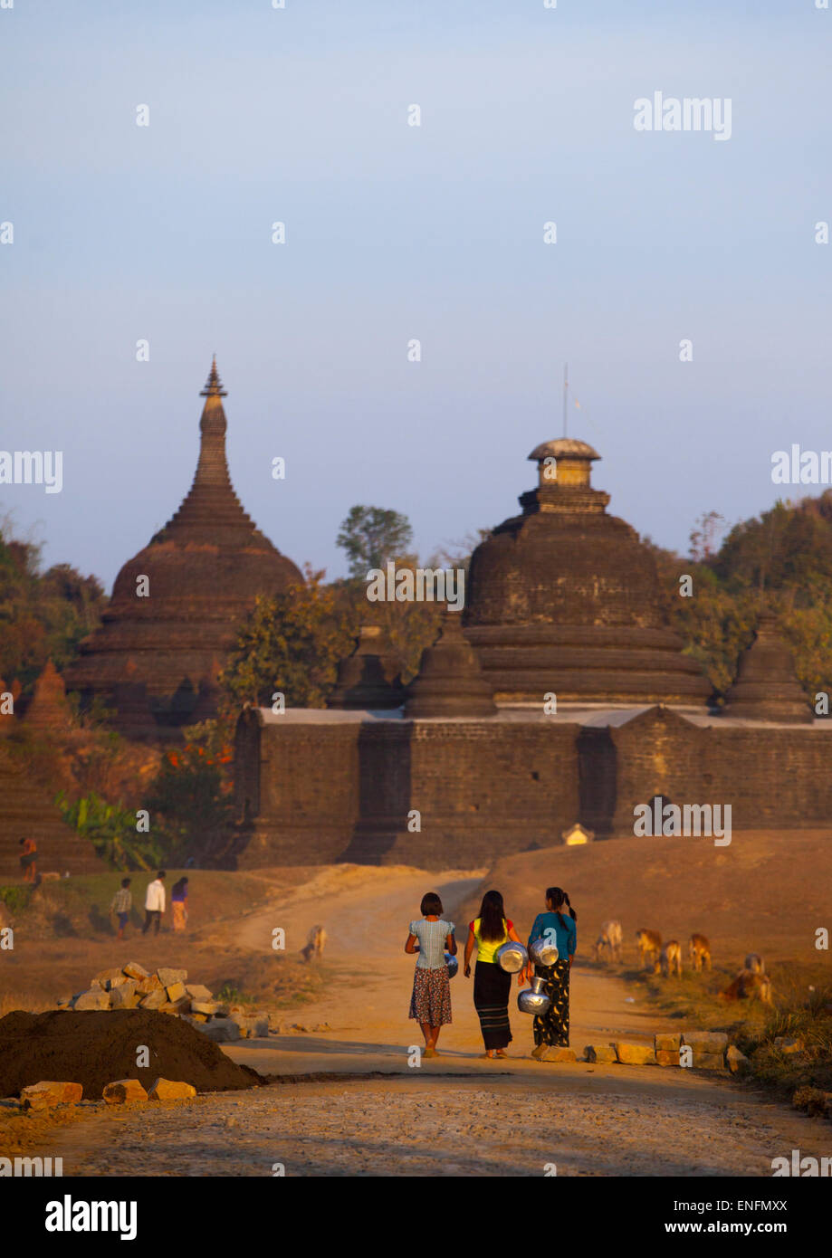 Les femmes portant de l'eau en face d'un temple bouddhiste, Mrauk U, Myanmar Banque D'Images