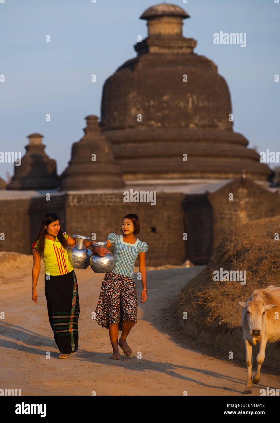 Les femmes portant de l'eau en face d'un temple bouddhiste, Mrauk U, Myanmar Banque D'Images