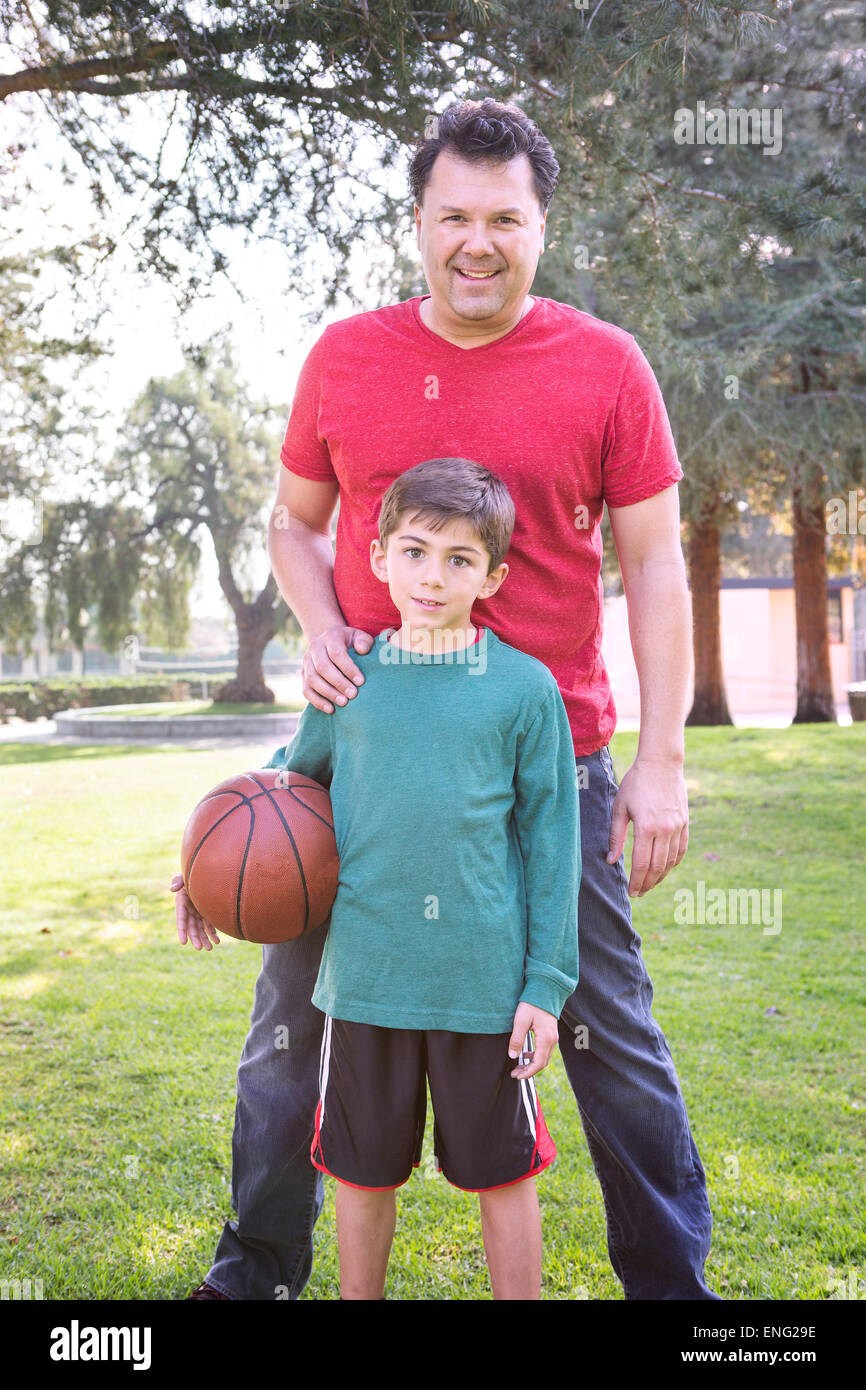 Caucasian father and son smiling in park with basketball Banque D'Images