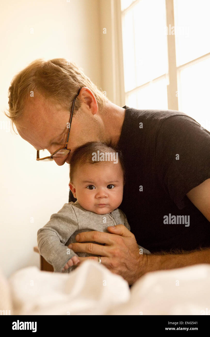 Father kissing baby boy on bed Banque D'Images