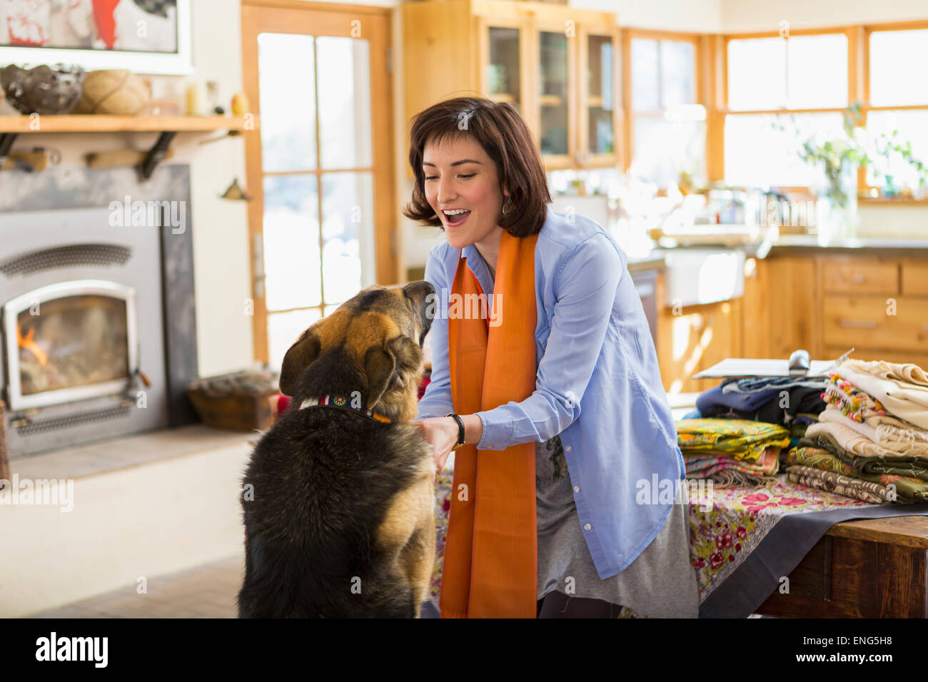 Hispanic woman petting dog in kitchen Banque D'Images