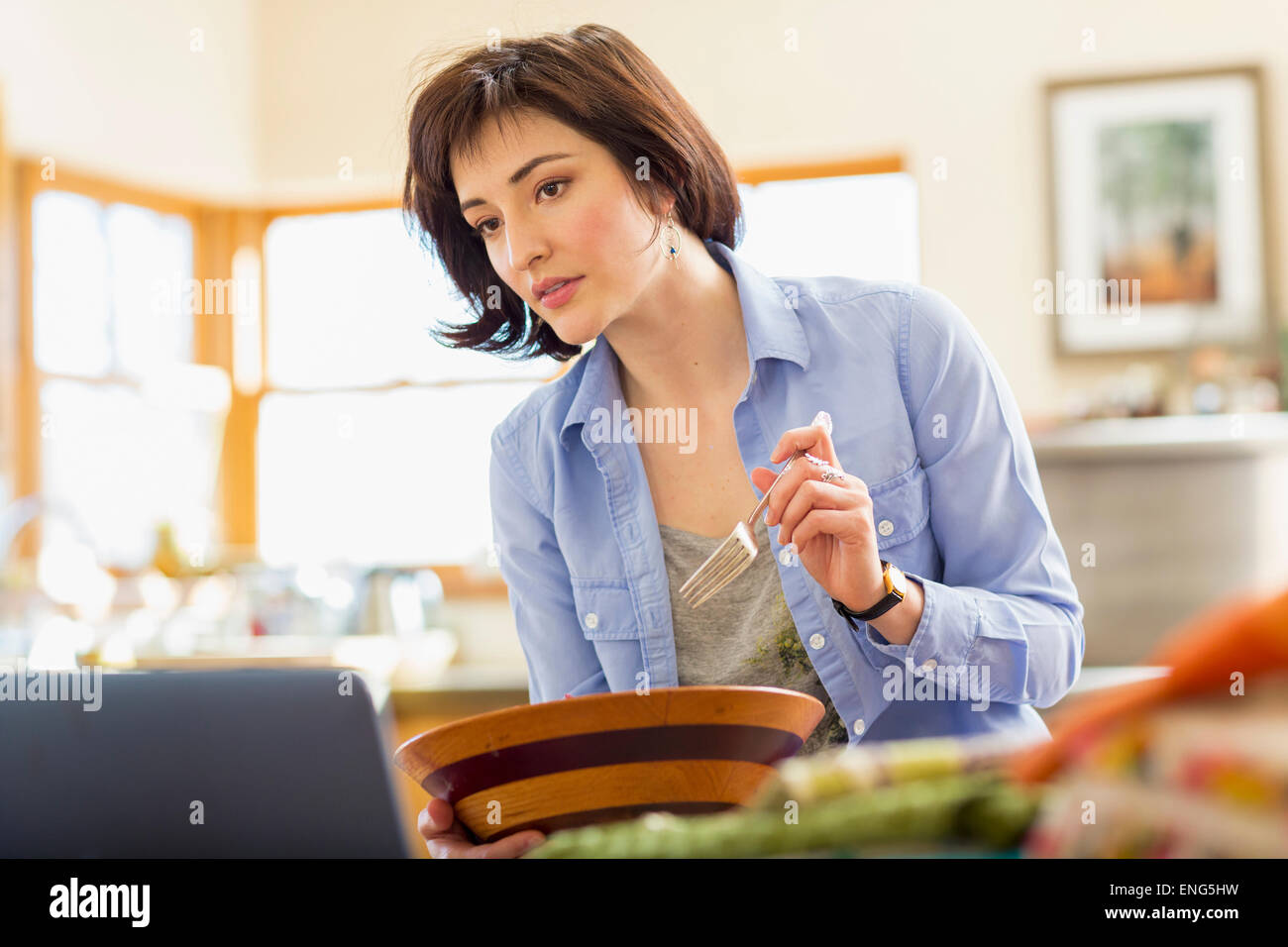 Propriétaire d'entreprise hispanique eating salad in home office Banque D'Images