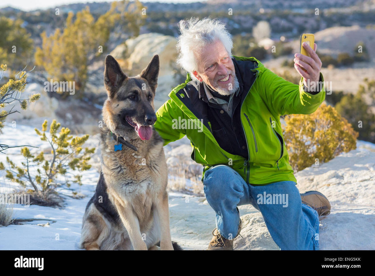 Homme plus âgé prendre cell phone photographie avec chien sur rock formations Banque D'Images