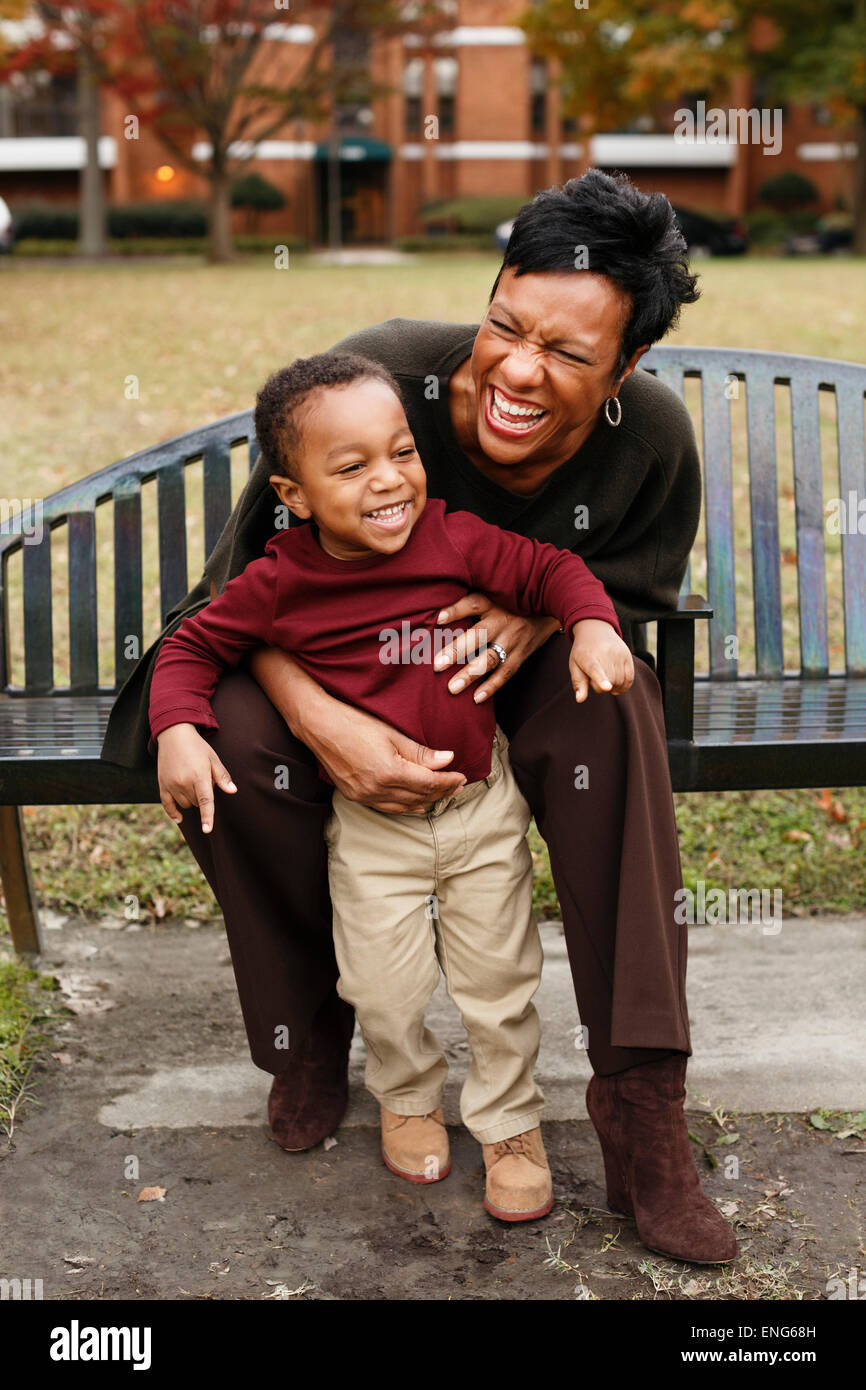 African American mother and son playing on park bench Banque D'Images