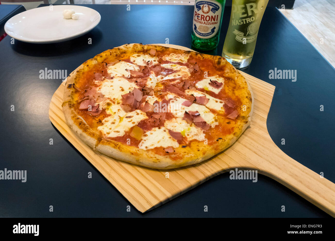 Pizza au jambon, mozzarella et sauce tomate servi avec une bière un Italien dans une pizzeria Banque D'Images