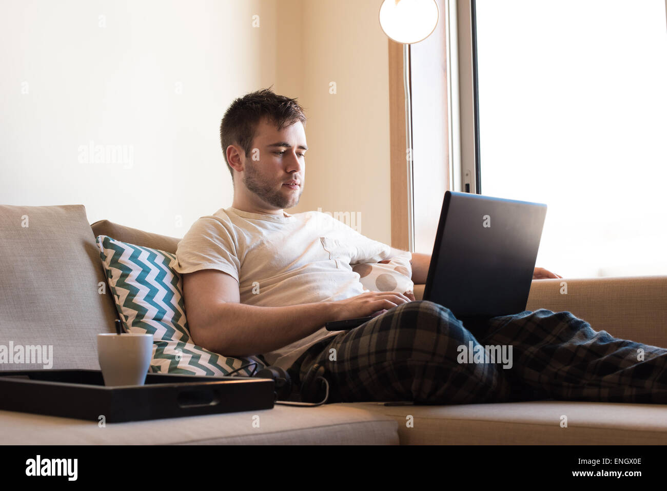 Homme assis sur le canapé avec un ordinateur portable et une tasse de café Banque D'Images