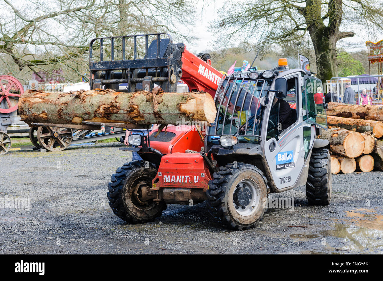 Un chariot élévateur Manitou ascenseurs un tronc d'arbre dans une scierie. Banque D'Images