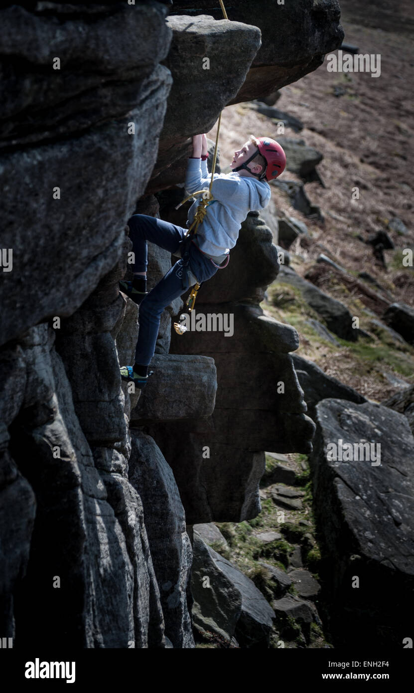 Un jeune garçon d'escalade sur Stanage Edge dans le Peak District Banque D'Images
