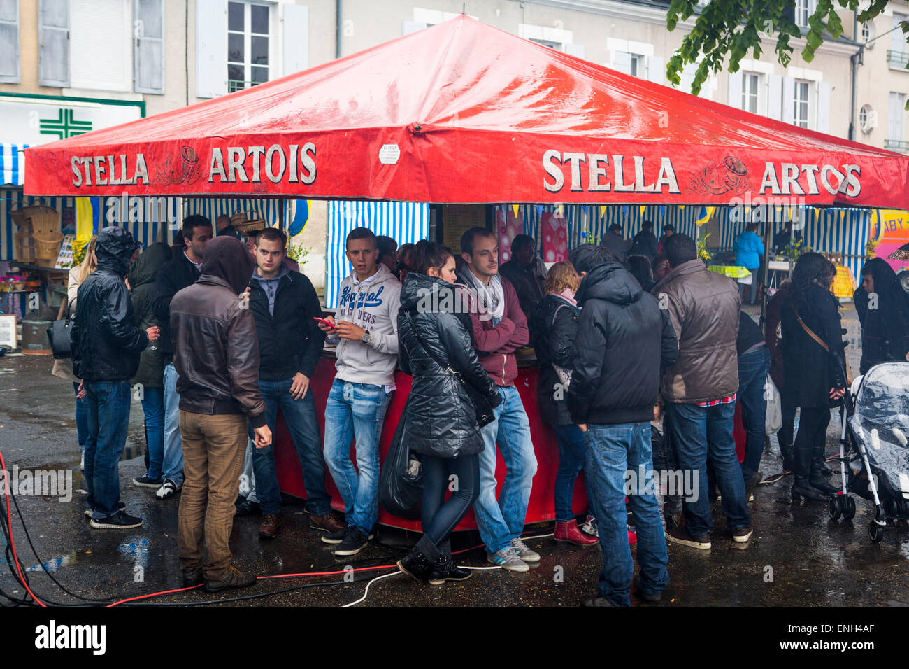 Ennuyer les adolescents rassemblement à un stand de bières pendant un jour de pluie à l'année marché de Mennetou-sur-Cher, France Banque D'Images