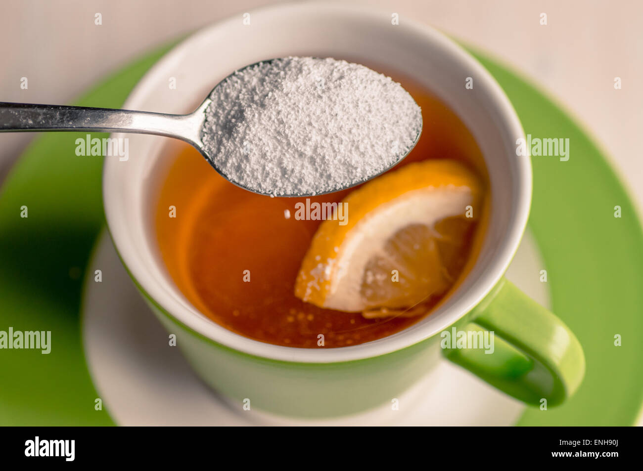 Édulcorant est versé depuis une cuillère dans une tasse de thé Banque D'Images