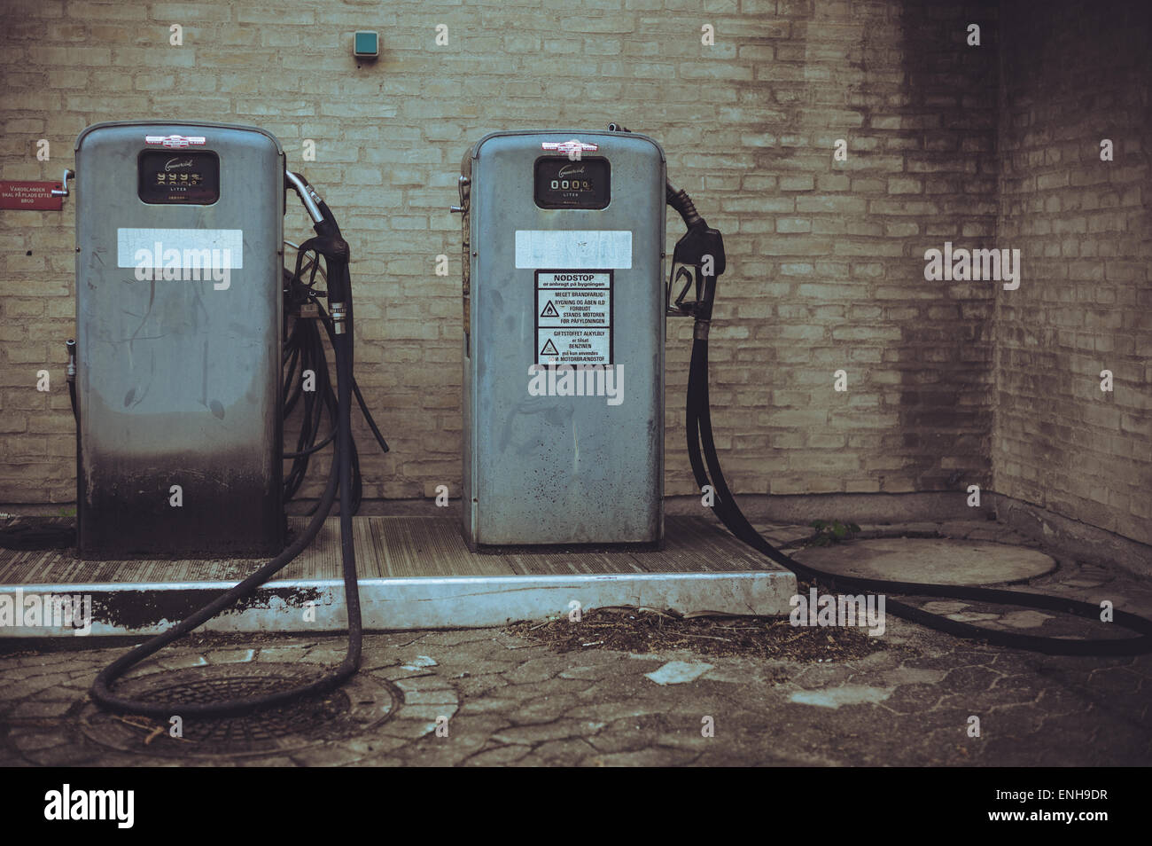 2 pompes à essence vintage, une avec une étiquette d'avertissement en danois Banque D'Images