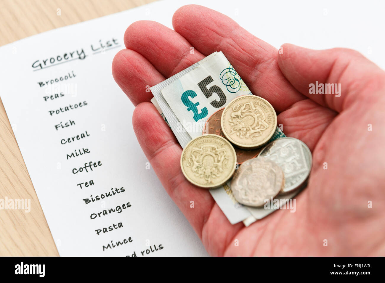 Une femme pauvre retraité senior une petite quantité d'argent comptant libre de faible valeur dans la main avec une liste de courses pour l'épicerie. England UK Banque D'Images