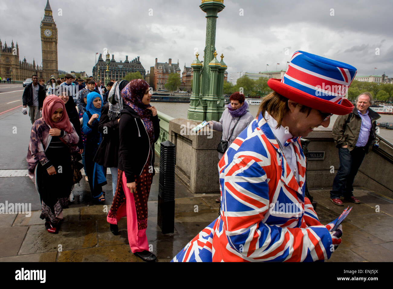 Des vents forts et les conditions météorologiques humides herald une semaine d'incertitude dans la Bretagne à moins de 24 heures avant l'élection générale. Peu probable que les perspectives d'un gouvernement majoritaire à la fin de la semaine, les offres d'orageuses entre les partis et le mécontentement des électeurs. Un dépliant touristique homme habillé en union jacks donne des détails d'un poisson et à proximité d'affaires à puce, en face du Palais de Westminster de Westminster Bridge. Banque D'Images