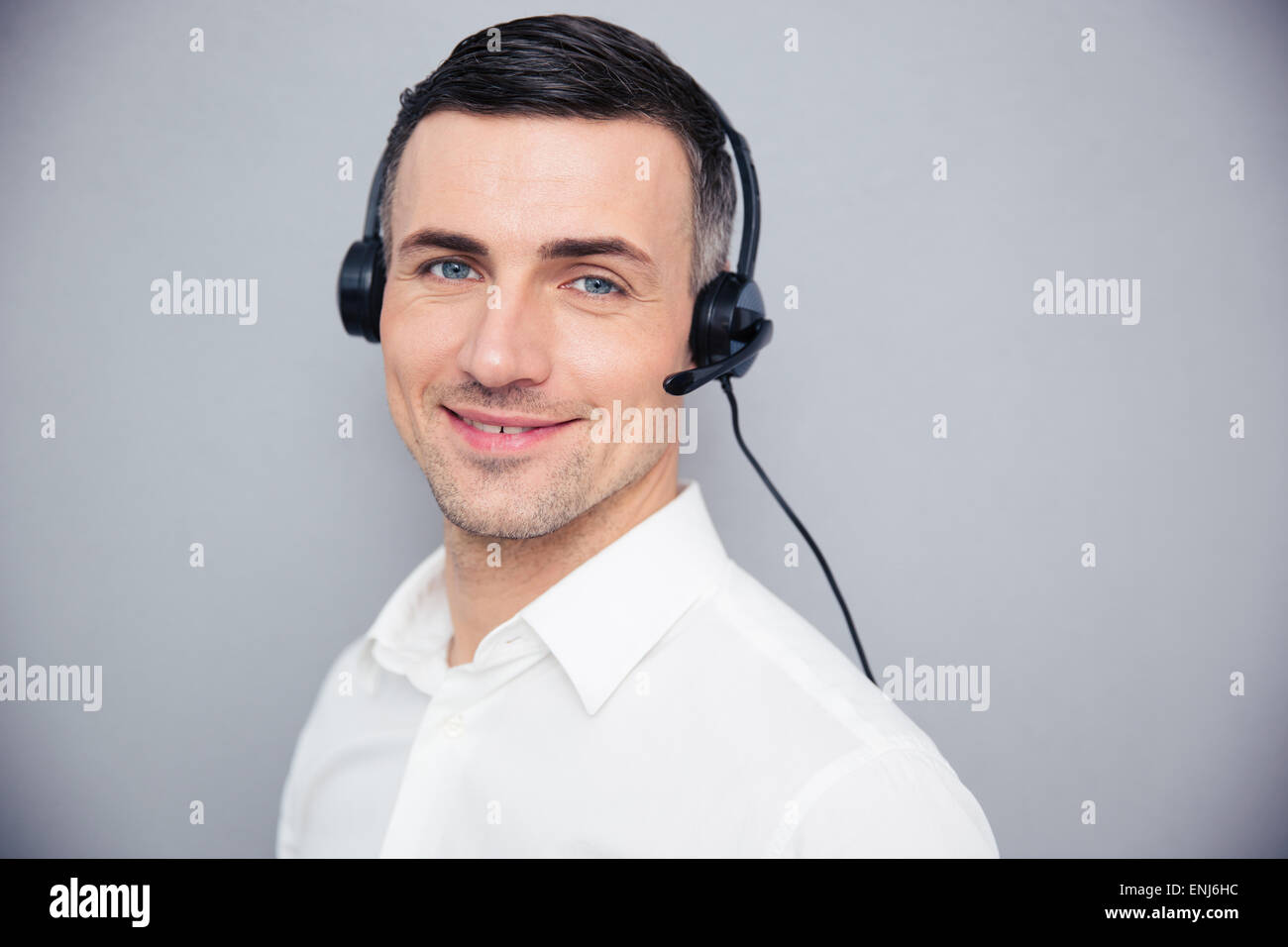 Happy young woman in headphones sur fond gris. Looking at camera Banque D'Images