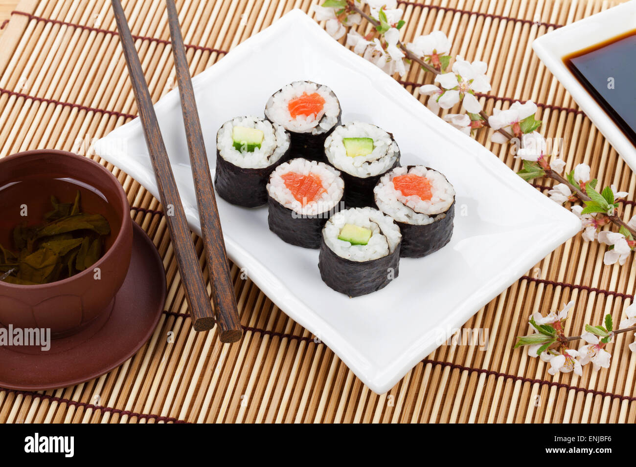 Sushi maki set, thé vert et sakura branche sur table en bambou Banque D'Images