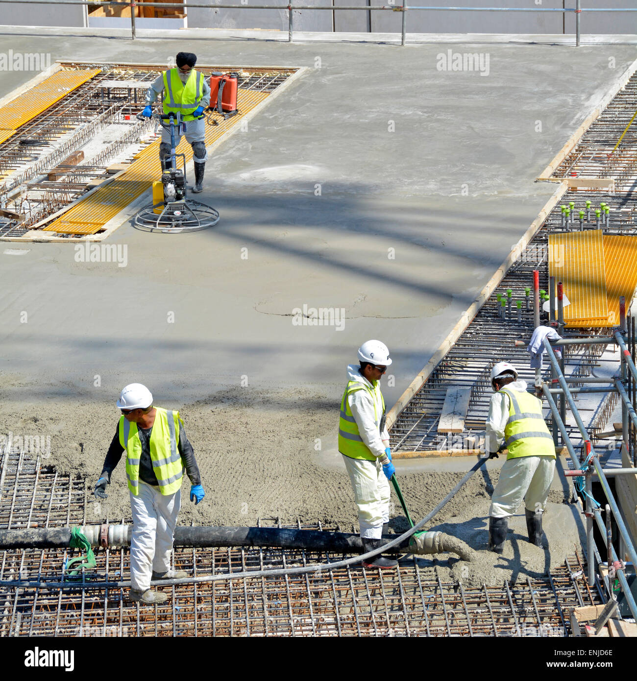 Construction de bâtiments site de l'industrie place et vibrent le béton pompé dans le renforcement avec des travailleurs de flotteur de puissance finissant la dalle lisse de sol Londres Royaume-Uni Banque D'Images