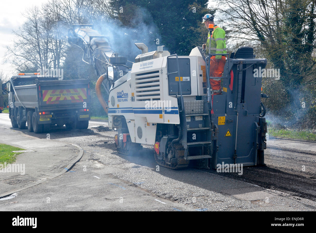 & Défectueux usé route asphaltée d'être raboté off en préparation d'un nouveau revêtement de chargement de camions à benne basculante pour le recyclage des déchets Brentwood Essex England UK Banque D'Images