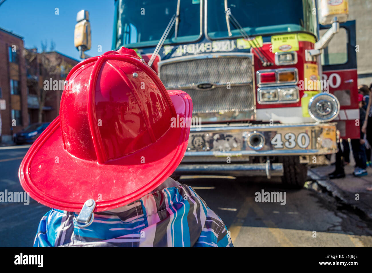 Enfant avec un casque de chasse-feu devant un camion d'incendie à Montréal, Canada Banque D'Images