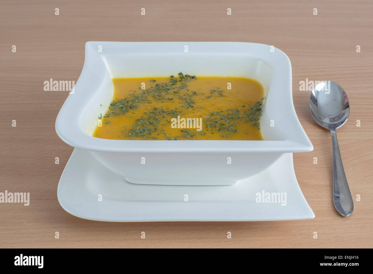 Soupe de carottes fait maison avec de la coriandre dans un bol en forme de carré blanc Banque D'Images