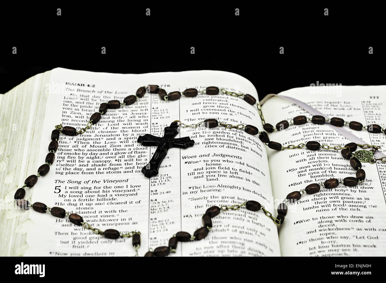 Vintage rosaire et crucifix sur Bible ouverte à Ésaïe sur fond noir Banque D'Images