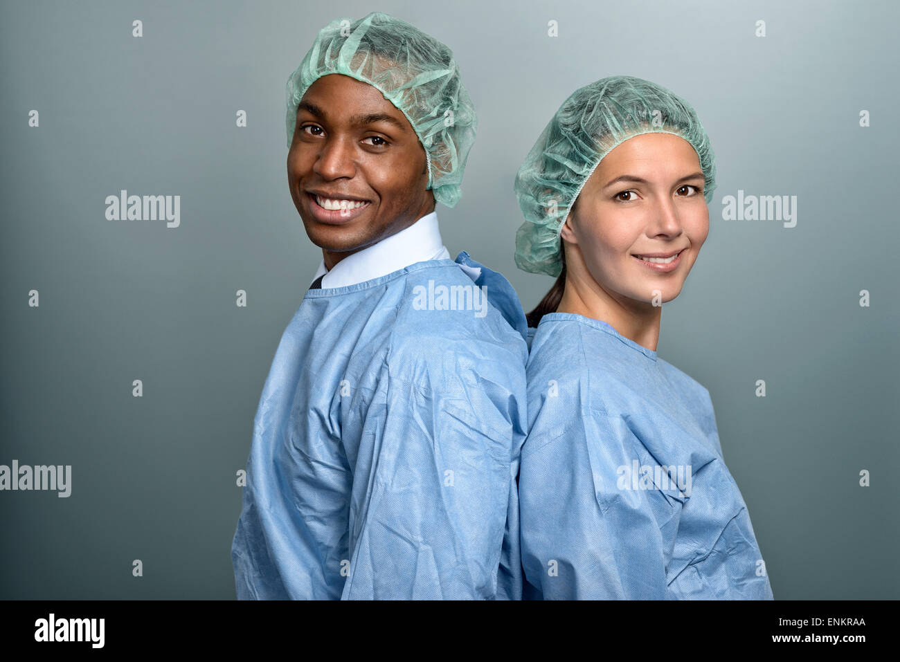 Beau jeune homme africain médecin ou infirmière dans scrubs et un chapeau de la stérilité à la recherche directement sur la caméra sur un fond gris Banque D'Images