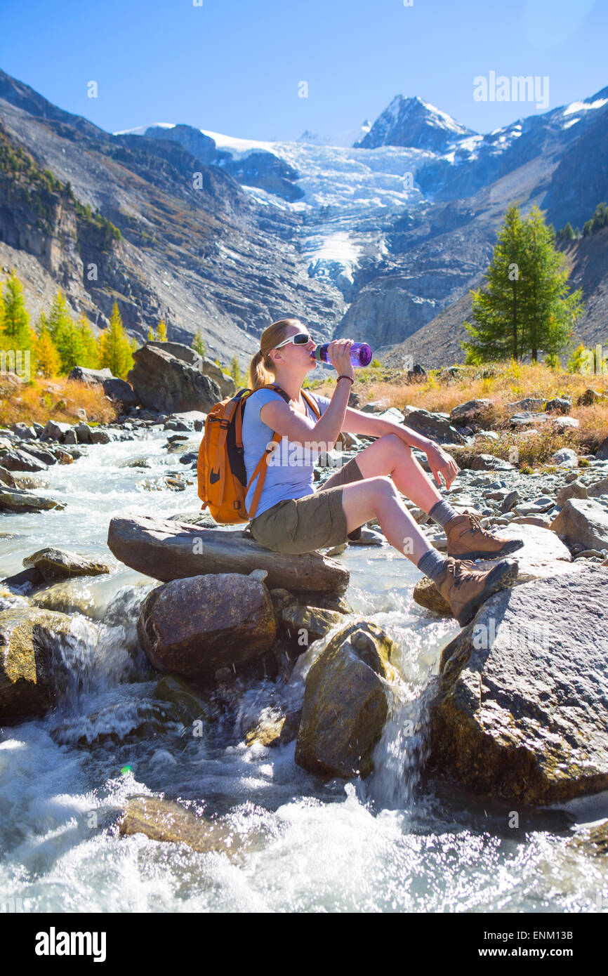 Un female hiker relaxing près d'une rivière de glacier dans les Alpes suisses. Banque D'Images