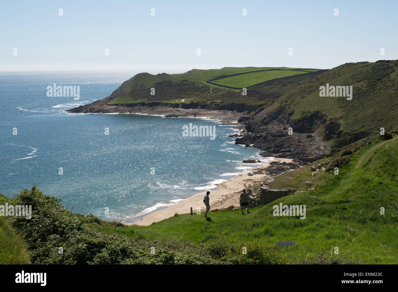 Couple en train de marcher sur le gazon couvert chemin falaise à l'abri de la baie de l'automne au-dessus de la mer scintillante bleu avec pointe et de champs. Banque D'Images