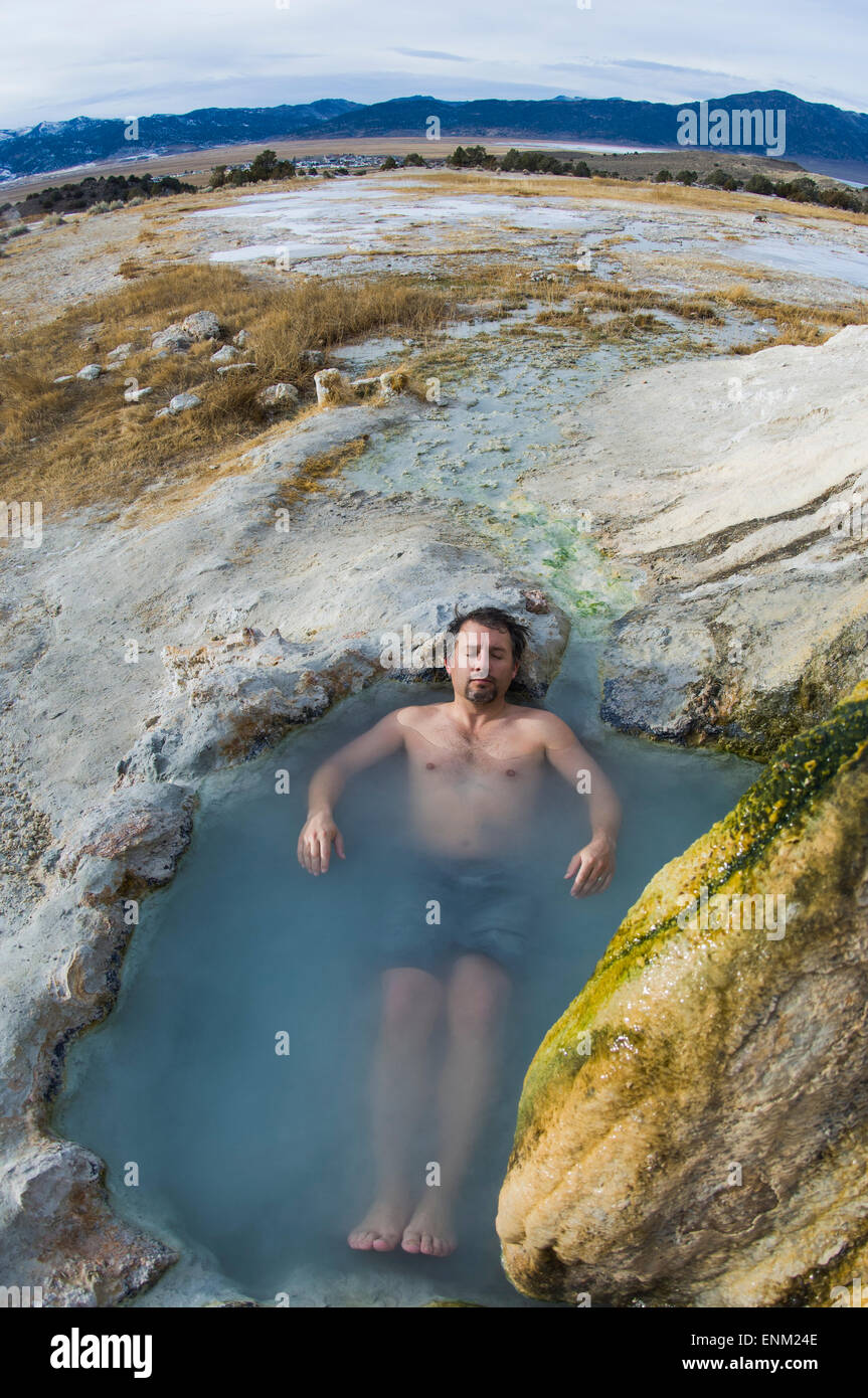 Man se détend dans Travertine Hot Springs pendant l'hiver dans l'est de Sierras, Californie. Banque D'Images