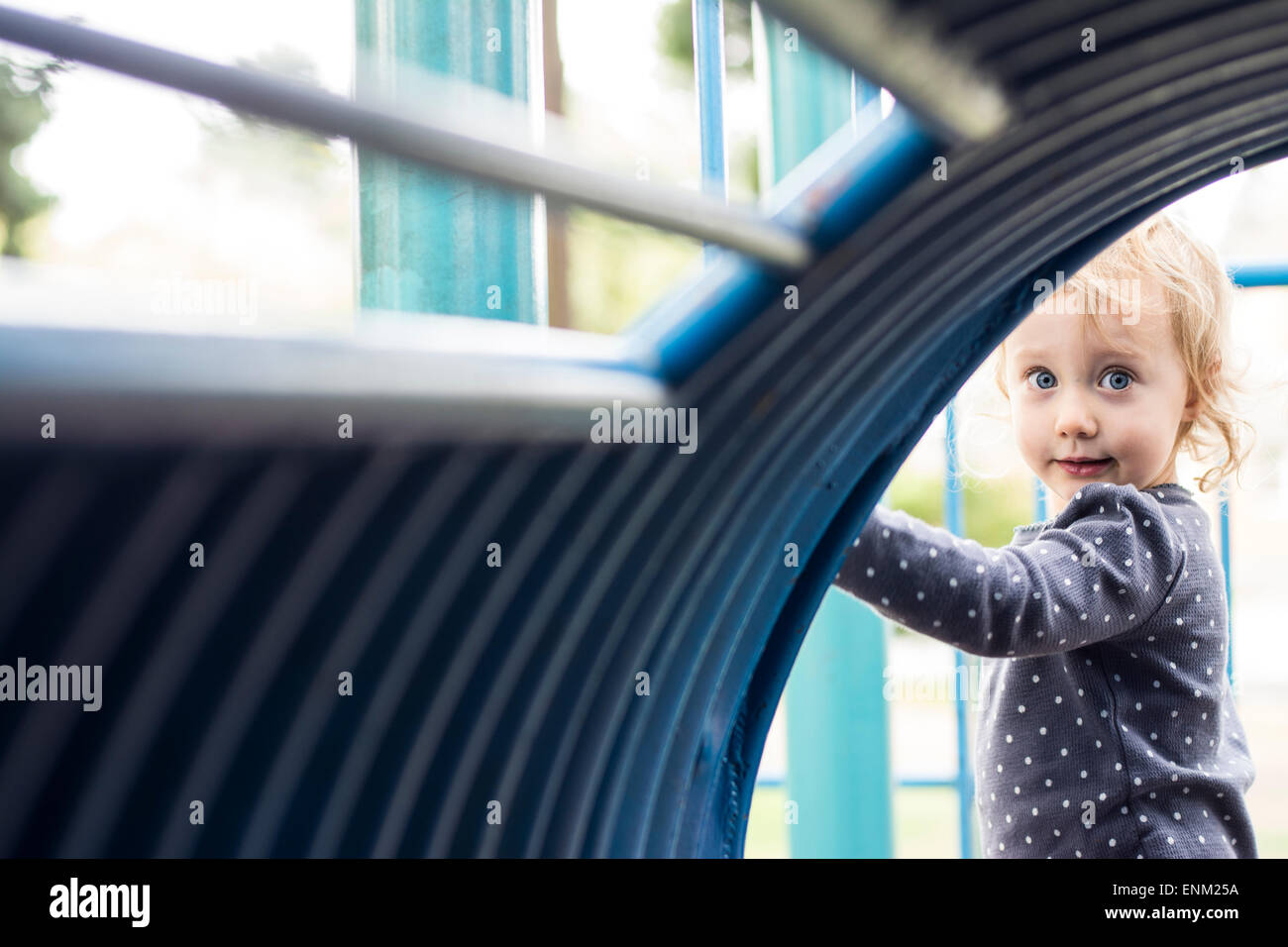 Bébé fille regarde par blue tunnel au jeu pour enfants à Portland, Oregon. Banque D'Images