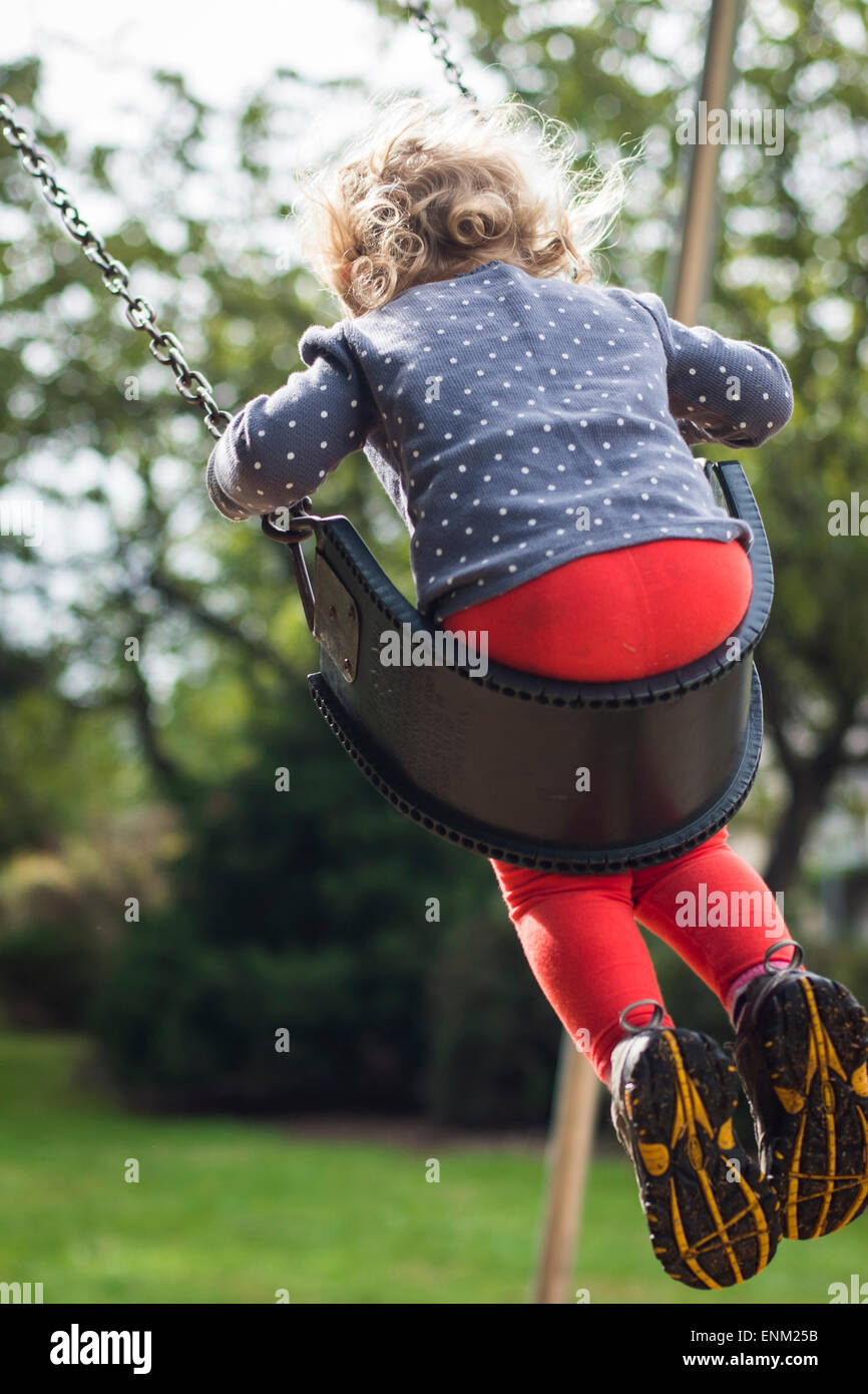 L'arrière du tout-petit fille se balançant à grande aire de jeux à Portland, Oregon. Banque D'Images