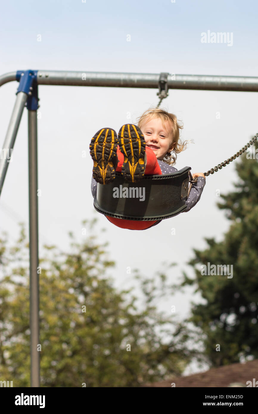 Smiling girl swinging élevée au niveau du jeu pour enfants à Portland, Oregon. Banque D'Images