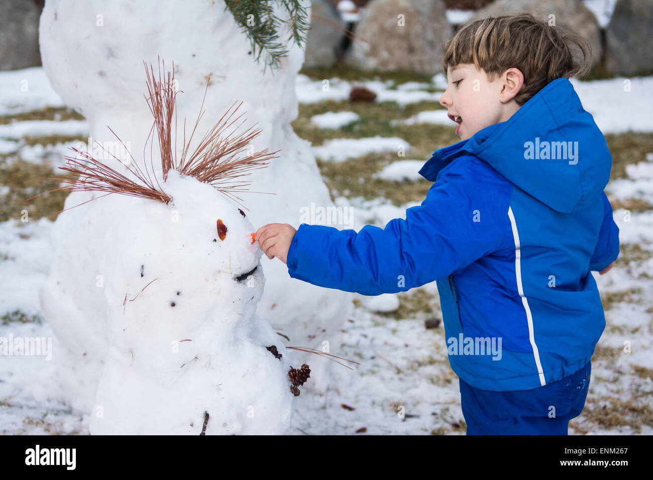 Bébé garçon décore snowman avec nez de carotte au début du printemps dans le lac Tahoe, en Californie. Banque D'Images