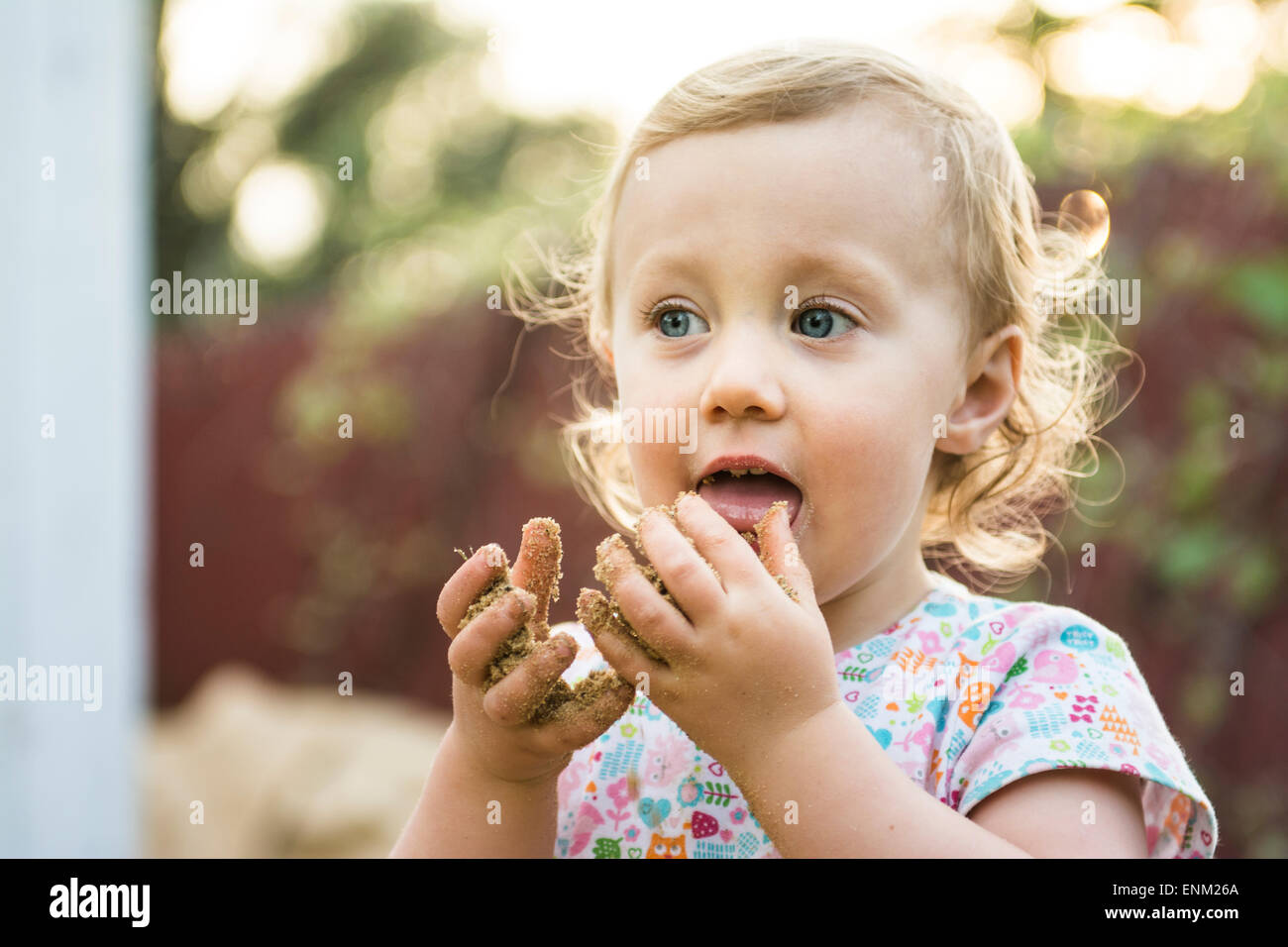 Bébé fille goûte le sable de mains, Chico, Californie. Banque D'Images