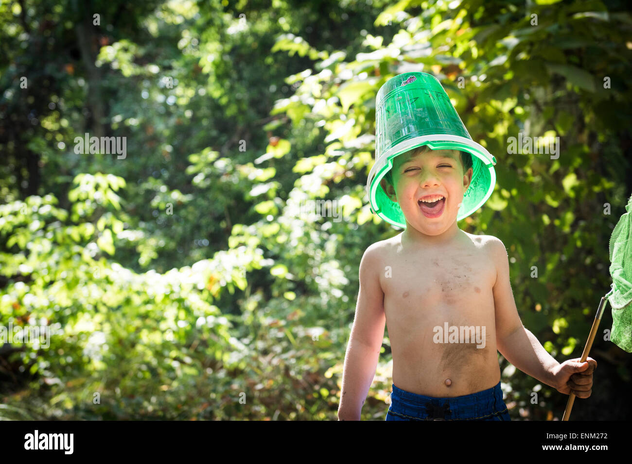 Bébé garçon des blagues avec un seau sur la tête et filet à papillons à la main alors qu'à côté de Creek dans le parc Bidwell, Chico, Californie. Banque D'Images