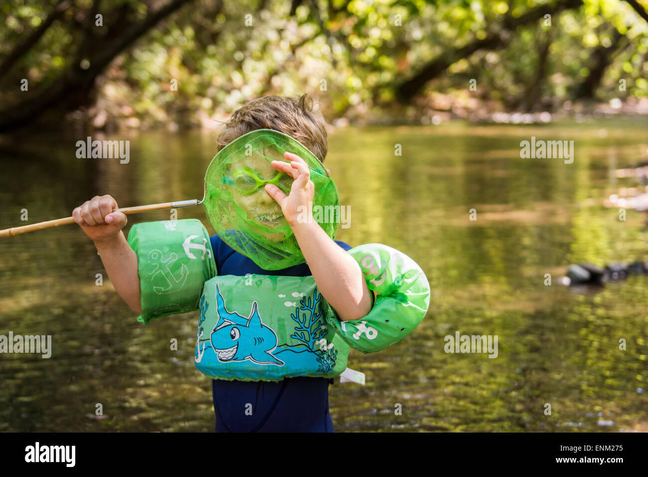 Bébé garçon avec floatie et lunettes caméra espions grâce à net dans creek à Bidwell Park, Chico, Californie. Banque D'Images