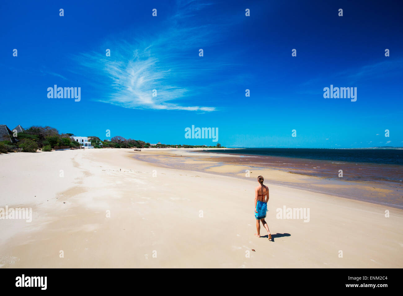 L'ÎLE DE MANDA, Lamu, l'OCÉAN INDIEN, le KENYA, l'Afrique. Une jeune femme marche dans une plage blanche vide sous ciel bleu. Banque D'Images