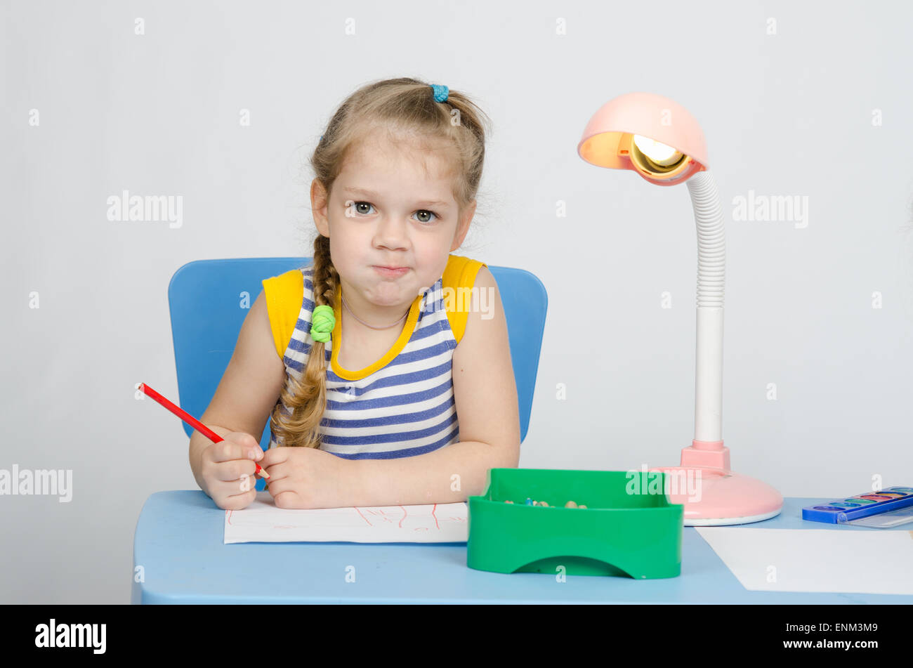 Fille de quatre ans attire les Européens crayon sur une feuille, assis à la table Banque D'Images